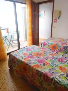 1 dormitorio con 2 camas y manta de flores en Pensión Los Volcanes, en Fuencaliente de la Palma