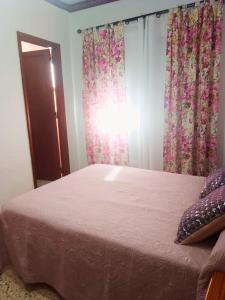 a bedroom with a bed with pink sheets and curtains at Pensión Los Volcanes in Fuencaliente de la Palma