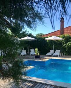 a swimming pool with two umbrellas and two chairs at Casa Stavros in 2 Mai