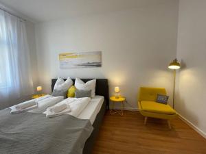 a bedroom with a bed and a yellow chair at LUCKY STAYS LS01 - 2 Zimmer - Luxus - Zentrum - große Küche - Aufzug - Smart-TV in Magdeburg
