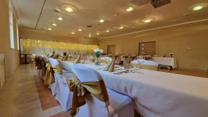 un gran salón de banquetes con mesas y sillas blancas en Aphrodite Hotel en Göd