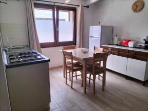a kitchen with a table and chairs and a refrigerator at Dimora al parco in Domusnovas