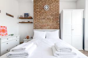 a bedroom with a white bed and a brick wall at Chic and Cheerful Flat in Willesden Green in London
