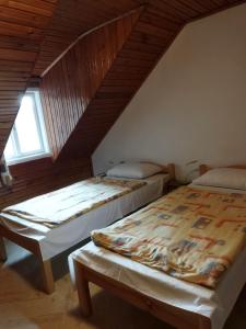 two beds in a room with a attic at Mecsek Virágai Lak in Magyarhertelend