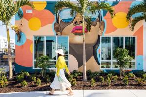 una mujer pasa por delante de un mural de una mujer con cara en Mint House St. Petersburg - Downtown, en San Petersburgo