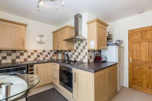 a kitchen with wooden cabinets and a glass table at Fern Hse Grassington; central yet quiet & parking in Grassington