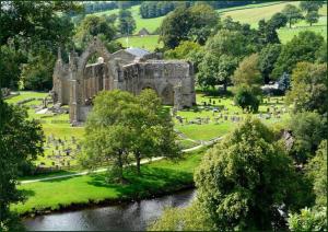 un antiguo edificio con un cementerio al lado de un río en Fern Hse Grassington; central yet quiet & parking en Grassington