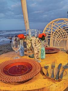 una mesa de madera con platos y copas de vino en la playa en Hotel Playa Paraiso en Dibulla