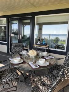 a table and chairs on a patio with windows at Saanichton Waterfront 2BR suite with superb views in Saanichton