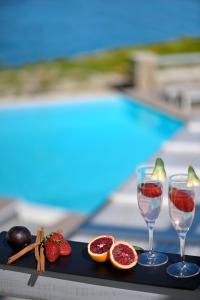 Una bandeja con fruta y copas de vino junto a una piscina. en Villa Indigo - Mykonos, en Mykonos ciudad