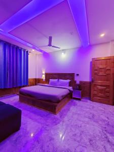 a bedroom with purple lighting and a bed and a dresser at Delight Homestay Kasol in Kasol
