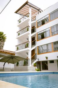 an apartment building with a swimming pool and an umbrella at Baños del Inca Premium Hotel in Los Baños del Inca