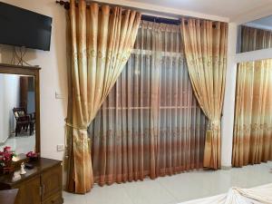 a large window with curtains in a bedroom at Nesh Villa in Aluthgama