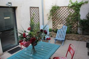uma mesa azul com um vaso de flores e duas cadeiras em Gites de Climats de 3 à 6 personnes em Beaune