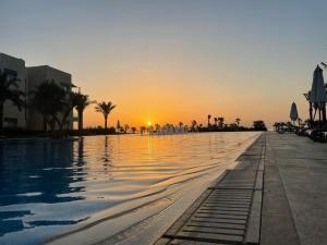 a swimming pool with a sunset in the background at Luxurious Sea view 2 BR & private Garden to the pool at Mangroovy in Hurghada