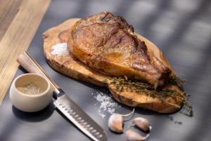a piece of meat on a wooden cutting board with a knife at Les Regalia Hôtel & Spa in Sainte-Lucie de Porto-Vecchio