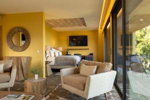 a living room with yellow walls and a bedroom at Les Regalia Hôtel & Spa in Sainte-Lucie de Porto-Vecchio