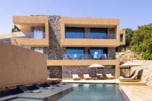 a villa with a swimming pool in front of a building at Les Regalia Hôtel & Spa in Sainte-Lucie de Porto-Vecchio
