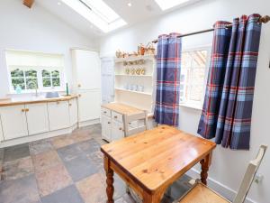 a kitchen with a wooden table and a bench at Pat's Cottage in Market Rasen