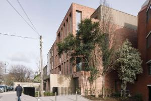 un homme marchant devant un bâtiment en briques dans une rue dans l'établissement Huband Place, à Dublin