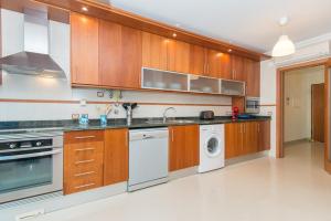 a kitchen with wooden cabinets and a washer and dryer at Casa Mergoux - Maravilhoso Apartamento em Tavira in Tavira