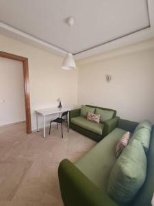 ein Wohnzimmer mit einem grünen Sofa und einem Tisch in der Unterkunft Immense appartement familial lumineux haut de l Agdal in Rabat