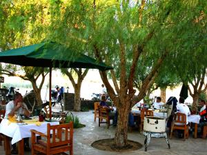 a group of people sitting at tables under a tree at Gondwana Canyon Roadhouse in Stamprivier