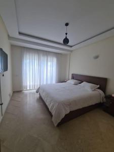 ein Schlafzimmer mit einem großen Bett und einem großen Fenster in der Unterkunft Immense appartement familial lumineux haut de l Agdal in Rabat