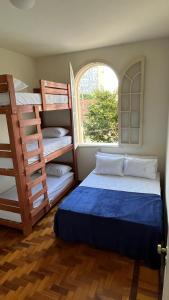 Nuh Hostel - Lourdes في بيلو هوريزونتي: غرفة نوم بسريرين بطابقين ونافذة