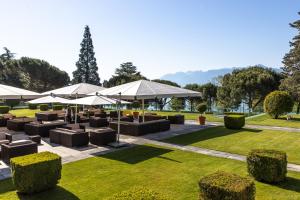 a patio with tables and umbrellas in a park at Beau-Rivage Palace in Lausanne