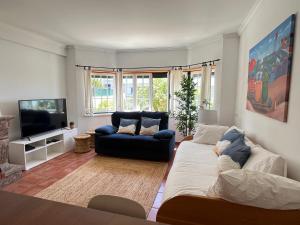 uma sala de estar com um sofá e uma televisão em Yellow House Ericeira na Ericeira