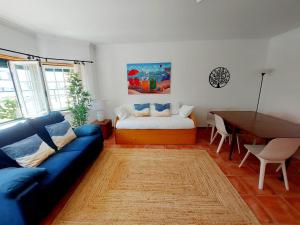 uma sala de estar com um sofá azul e uma mesa em Yellow House Ericeira na Ericeira