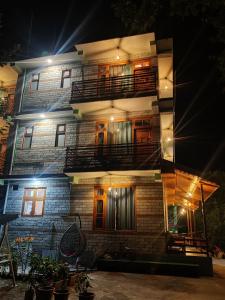 un edificio de ladrillo con balcones por la noche en Delight Homestay Kasol en Kasol