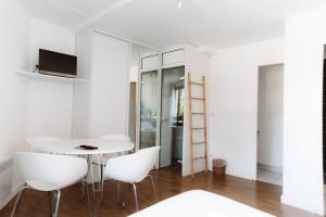 un comedor blanco con una mesa y sillas blancas en Hôtel Les Fougères, en Hossegor