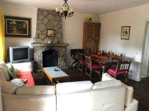 sala de estar con sofá, mesa y chimenea en Casa Rural Pantano de San Juan, en Pelayos de la Presa