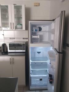 an empty refrigerator with its door open in a kitchen at Departamento para un buen descanso in Lima