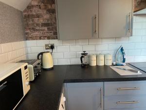 cocina con armarios blancos y encimera negra en Howe - Newly refurbished 2 bedroom flat Free Parking en Gateshead