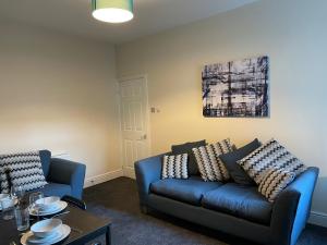 a living room with a blue couch and a table at Howe - Newly refurbished 2 bedroom flat Free Parking in Gateshead