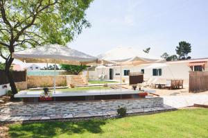 un patio con 2 sombrillas blancas en Tree House - 3 Casas Figueira Laranjeira Limoeiro en Sesimbra