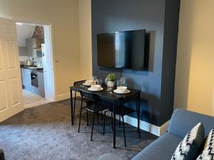 a living room with a table with chairs and a tv at Howe - Newly refurbished 2 bedroom flat Free Parking in Gateshead