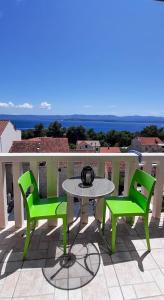 een tafel en 2 groene stoelen op een balkon bij Apartments Ivka Bol in Bol