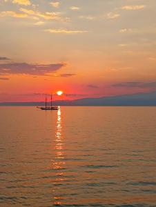 ein Boot im Ozean bei Sonnenuntergang in der Unterkunft Golden Sunset Beach Apartment in Skala Kallirachis