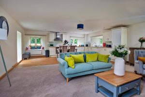 a living room with a blue couch and a kitchen at Finest Retreats - Victory Mill - Apartment One in Pickering