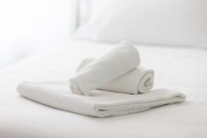 una pila de toallas blancas en un fondo blanco en Bnbook Residenza Locatelli, en Rho
