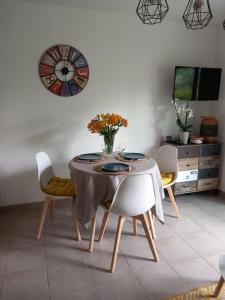 a dining room with a table and chairs and a clock at le loft de la riviéra in Bénodet