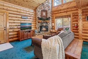 Cabaña de madera con sala de estar con sofá y TV. en Papa Bear's Hideout - Dream Getaway with Hot Tub and Game Room!, en Big Bear Lake