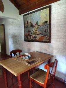 ein Holztisch mit zwei Stühlen und einem Gemälde an der Wand in der Unterkunft Molle in Villa Cura Brochero + 1 Foto
