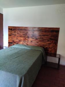 Bett in einem Schlafzimmer mit einem Kopfteil aus Holz in der Unterkunft Molle in Villa Cura Brochero
