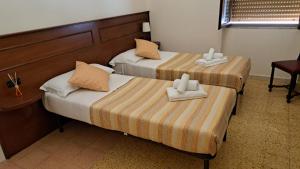 two beds in a hotel room with towels on them at Vittoria Guest House Battipaglia in Battipaglia