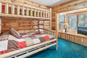 Dormitorio en cabaña de madera con litera y TV en Papa Bear's Hideout - Dream Getaway with Hot Tub and Game Room!, en Big Bear Lake